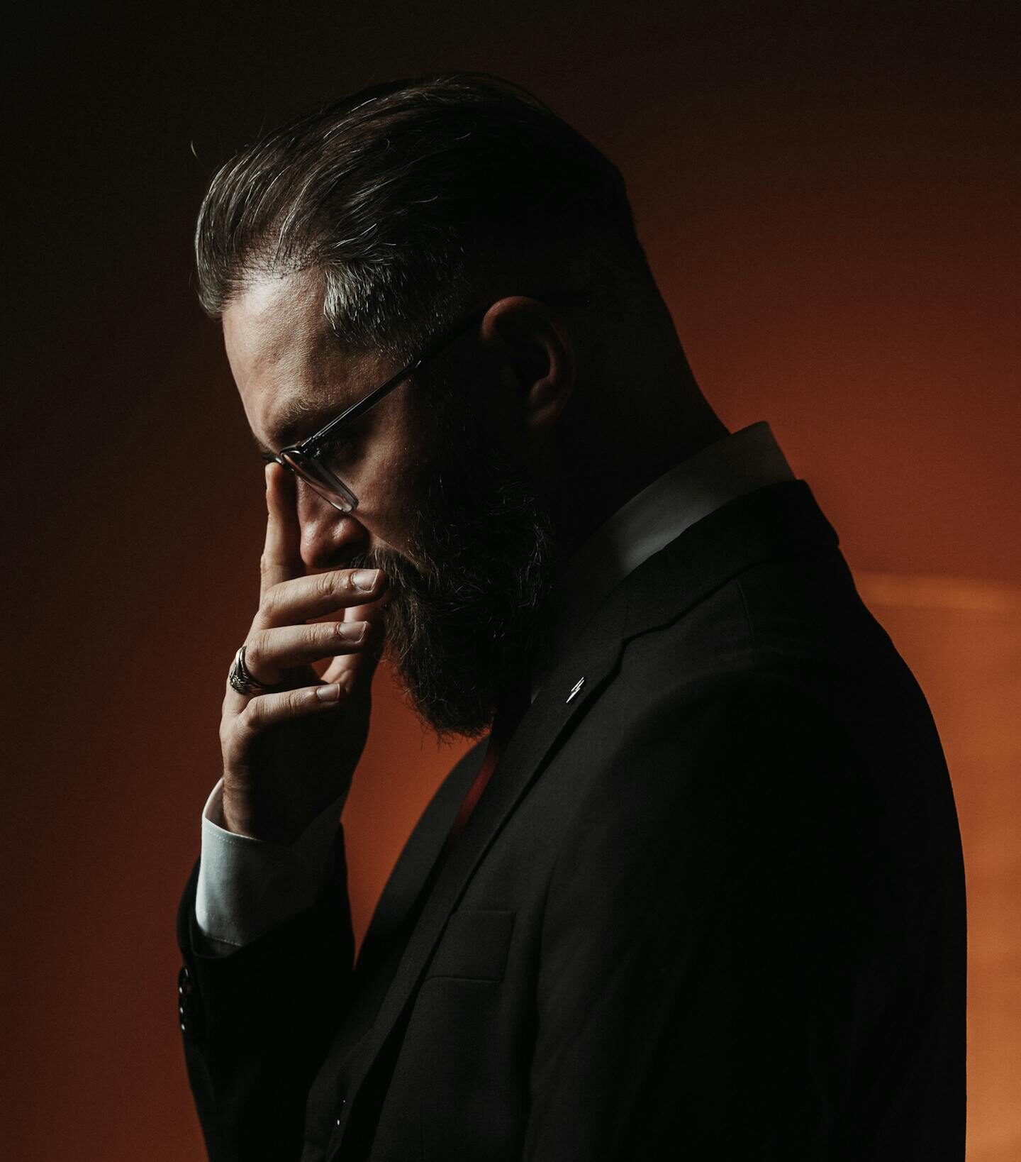 Side profile of thoughtful man in suit. Dramatic lighting creates an introspective mood.